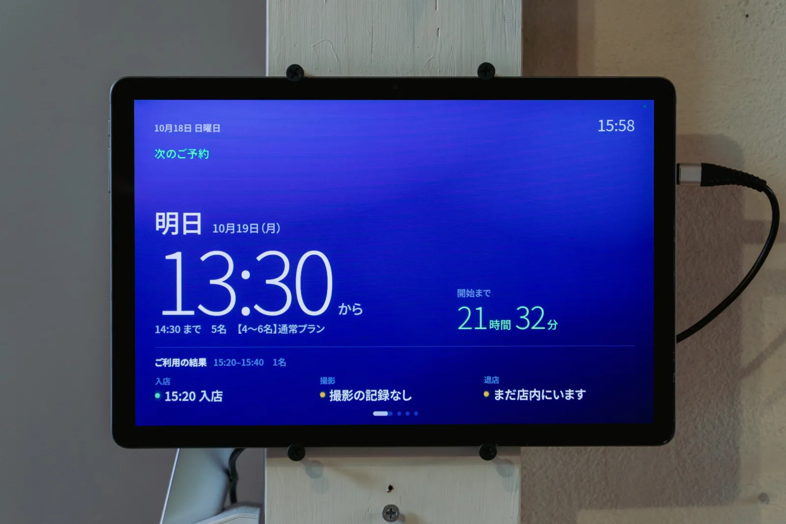 実家の柱に付けた10インチのタブレット。深い青の画面に、次のご予約の時刻と開始までの残り時間が大きく出ている